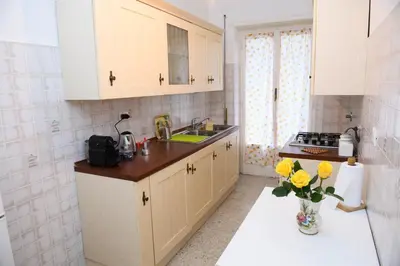 a kitchen with white cabinets and a vase of yellow flowers at Cesare a Trastevere in Rome