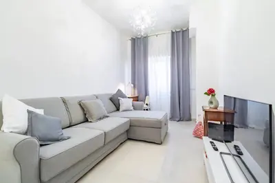 a white living room with a couch and a tv at Joy Home in Rome