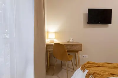 a bedroom with a desk with a chair and a television at Anastasia Comfort at the Vatican with Balcony in Rome