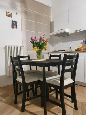 a dining room table with chairs and a vase of flowers at Casa Mari - Cozy Apartment San Paolo Rome in Rome