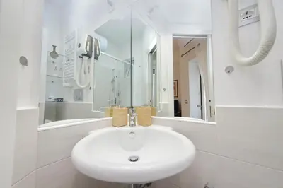 a white bathroom with a sink and a mirror at CasAchille Mini Studio in Rome