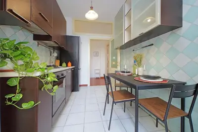 a kitchen with a table and chairs in a room at Modern Apartment near Metro Malatesta with Balcony & Wi-Fi in Rome