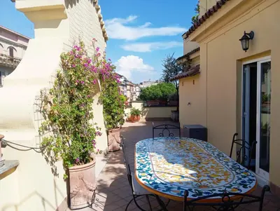 a patio with a table and flowers on a balcony at Vatican Penthouse - Terrace with view in Rome