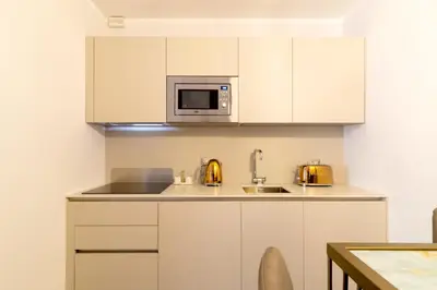a kitchen with white cabinets and a microwave at Casa Barbieri boutique apartment Borgo Pio in Rome