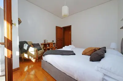 a bedroom with a white bed and a chair at Anastasio Spacious Apartment in Rome