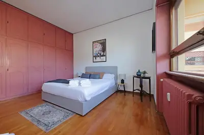 a bedroom with a white bed and pink walls at Anastasio Spacious Apartment in Rome