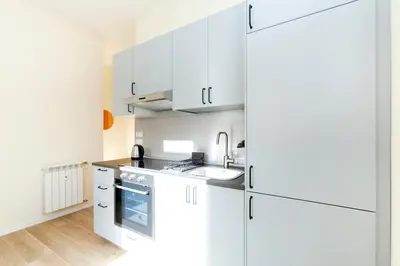 a white kitchen with a sink and a refrigerator at Trendy apartment at Vatican in Rome