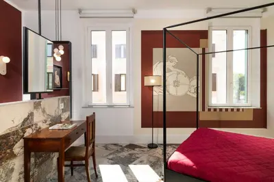 a bedroom with a red bed and a desk at Alma at Colosseum Luxury Apartment with View in Rome