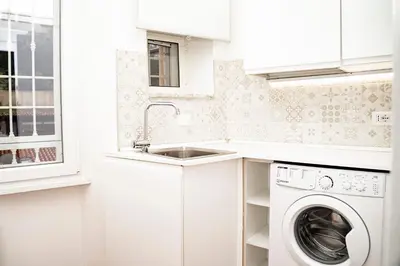 a white kitchen with a sink and a washing machine at Domina Apartments Roma - San Pietro 3 in Rome