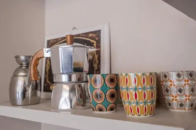 a shelf with a coffee pot and mugs on it at La Terrazza Loft near San Pietro in Rome