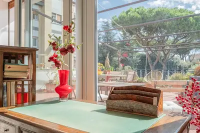a vase with flowers on a table in a room with a window at La Terrazza Loft near San Pietro in Rome