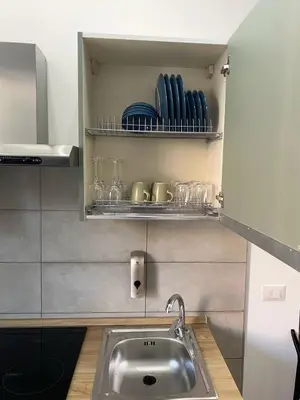 a kitchen with a sink and glasses on shelves at Domus Quadraro II in Rome