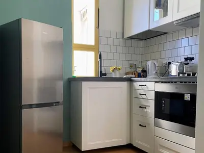 a kitchen with white cabinets and a stainless steel refrigerator at Bed Bike Breakfast Appartamento Piramide in Rome