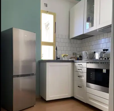 a kitchen with white cabinets and a stainless steel refrigerator at Bed Bike Breakfast Appartamento Piramide in Rome