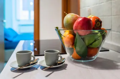 a bowl of fruit sitting on a table with two cups at Apartment Maria in Monti in Rome