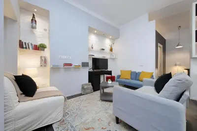 a living room with two white couches and a tv at Il Rifugio di Boezio by DomusDimore in Rome