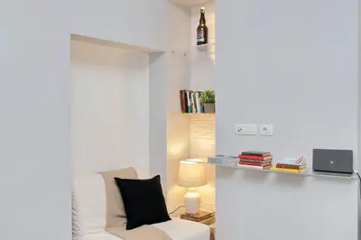 a white living room with a white chair and a lamp at Il Rifugio di Boezio by DomusDimore in Rome