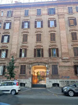 a large brick building with an entrance with cars parked in front at Apartment in Testaccio in Rome