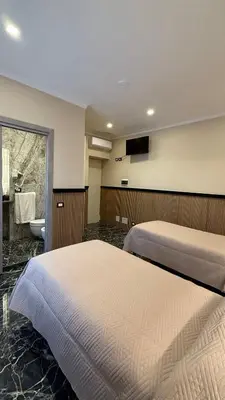 a bedroom with two beds and a bathroom with a sink at Bed and Breakfast Eritrea in Rome