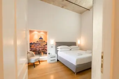 a white bedroom with a bed and a chair at Amor Guest House San Giovanni in Rome