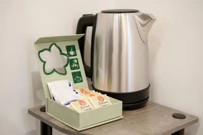 a coffee pot and a box on a wooden table next to a coffee maker at Amor Guest House San Giovanni in Rome