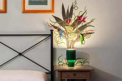a vase with flowers on a table next to a bed at Silenzioso, grande, comodo alloggio a Trastevere in Rome