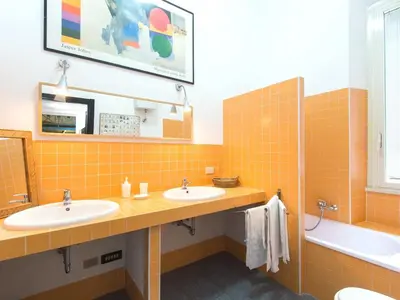 an orange tiled bathroom with two sinks and a tub at Silenzioso, grande, comodo alloggio a Trastevere in Rome