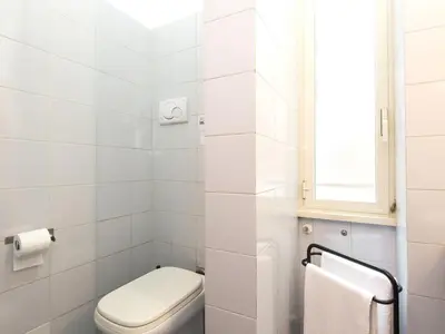 a white bathroom with a toilet and a window at Silenzioso, grande, comodo alloggio a Trastevere in Rome
