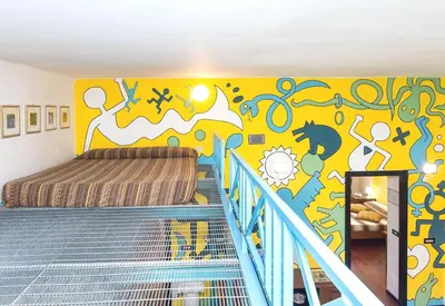 a bedroom with a yellow wall with a bed and a mural at Silenzioso, grande, comodo alloggio a Trastevere in Rome