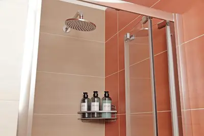 a shower with three bottles of wine on a shelf at Graceful Apartment near St Peter METRO 100 mt in Rome