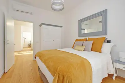 a white bedroom with a large bed with orange pillows at Graceful Apartment near St Peter METRO 100 mt in Rome