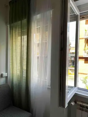 a window with curtains and a chair in a room at Nido rinnovato in Rome