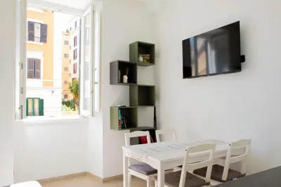 a white dining room with a white table and chairs at Casa Carmine in Trastevere in Rome