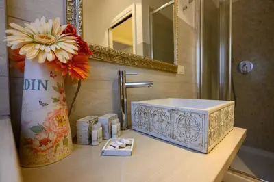 a bathroom with a sink and a vase with a flower at Vatican City Historic Center -Luxury Flat with Garden and Private Parking in Rome