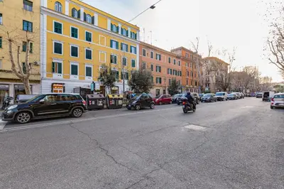 a person riding a motorcycle down a city street with cars at Modern flat in Vatican in Rome