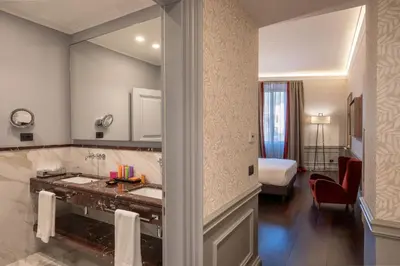 a bathroom with a sink and a room with a bed at The Inn at the Spanish Steps Elegant Collection - The Gem in Rome