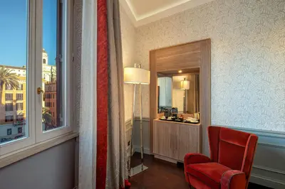 a room with a red chair and a window at The Inn at the Spanish Steps Elegant Collection - The Gem in Rome