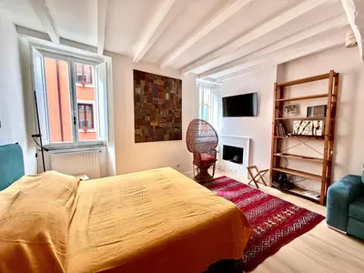 a bedroom with a bed and a chair and a tv at Colosseo Lovely studio apartment in Rome