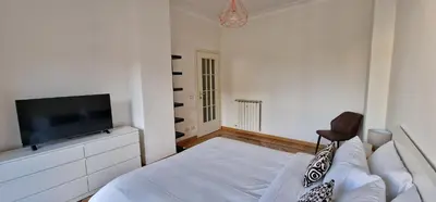 a white bedroom with a bed and a flat screen tv at Nox Romana Apartments - Saint Peter - Large Flat with Terrace in Rome