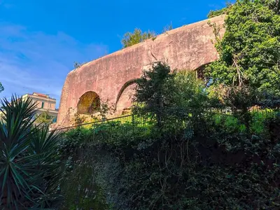 an old brick building with a fence and trees at La casa di Ricky in Rome