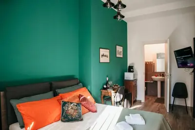 a bedroom with green walls and a bed with orange pillows at Vatican Suite 