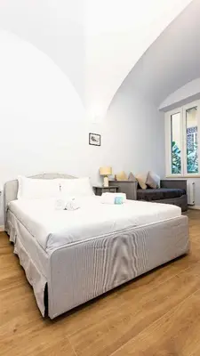 a white bedroom with a large bed and a couch at Monti Nonna Francesca - ZENO 49 in Rome