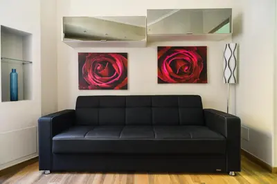 a black couch in a room with two paintings at Lata Luxury Apartment in Rome