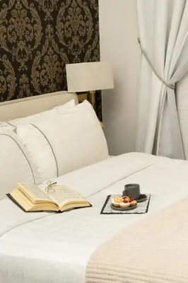 a book and a plate of food on a bed at STOA ROME Boutique Suites in Rome