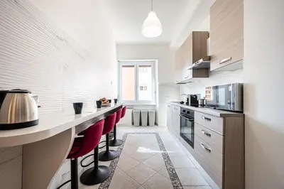a kitchen with a counter and some red chairs at Via Niso Apartment in Rome