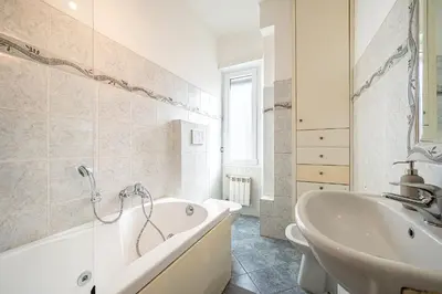 a white bathroom with a tub and a sink at Via Niso Apartment in Rome