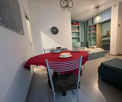 a dining room with a red table and a couch at Cozy Studio near Vaticano in Rome