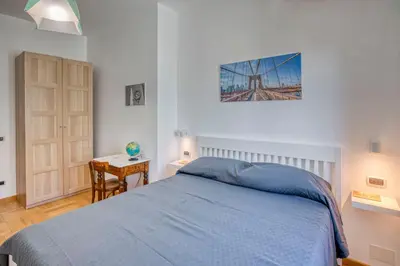 a bedroom with a bed with a blue blanket and a table at Dimora Savorelli, ampio appartamento zona Vaticano in Rome