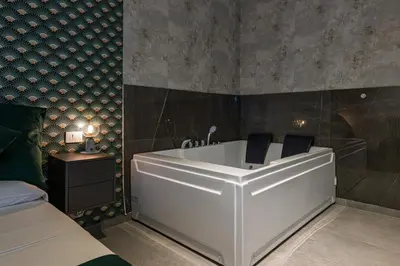 a bathroom with a white tub in a bedroom at Luxury Jacuzzi Suites Rome - You Rhome in Rome