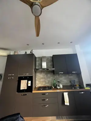 a kitchen with gray cabinets and a ceiling fan at Nathan House, Tuscolana in Rome